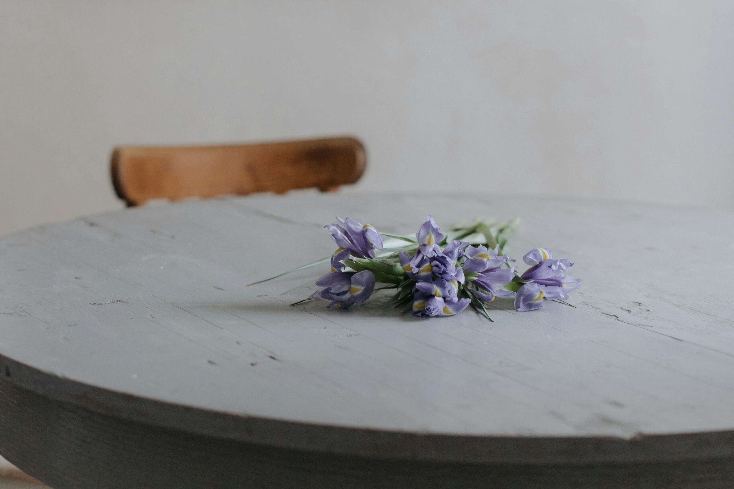 A bunch of lavender iris flowers rest delicately on a rustic wooden table, evoking a tranquil mood.